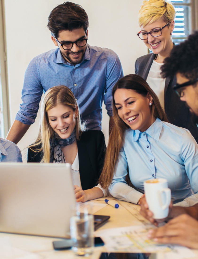 La felicità nei luoghi di lavoro: colleghi che sorridono davanti a un computer